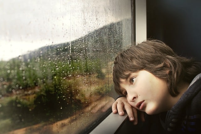 Niño mirando la lluvia por la ventana