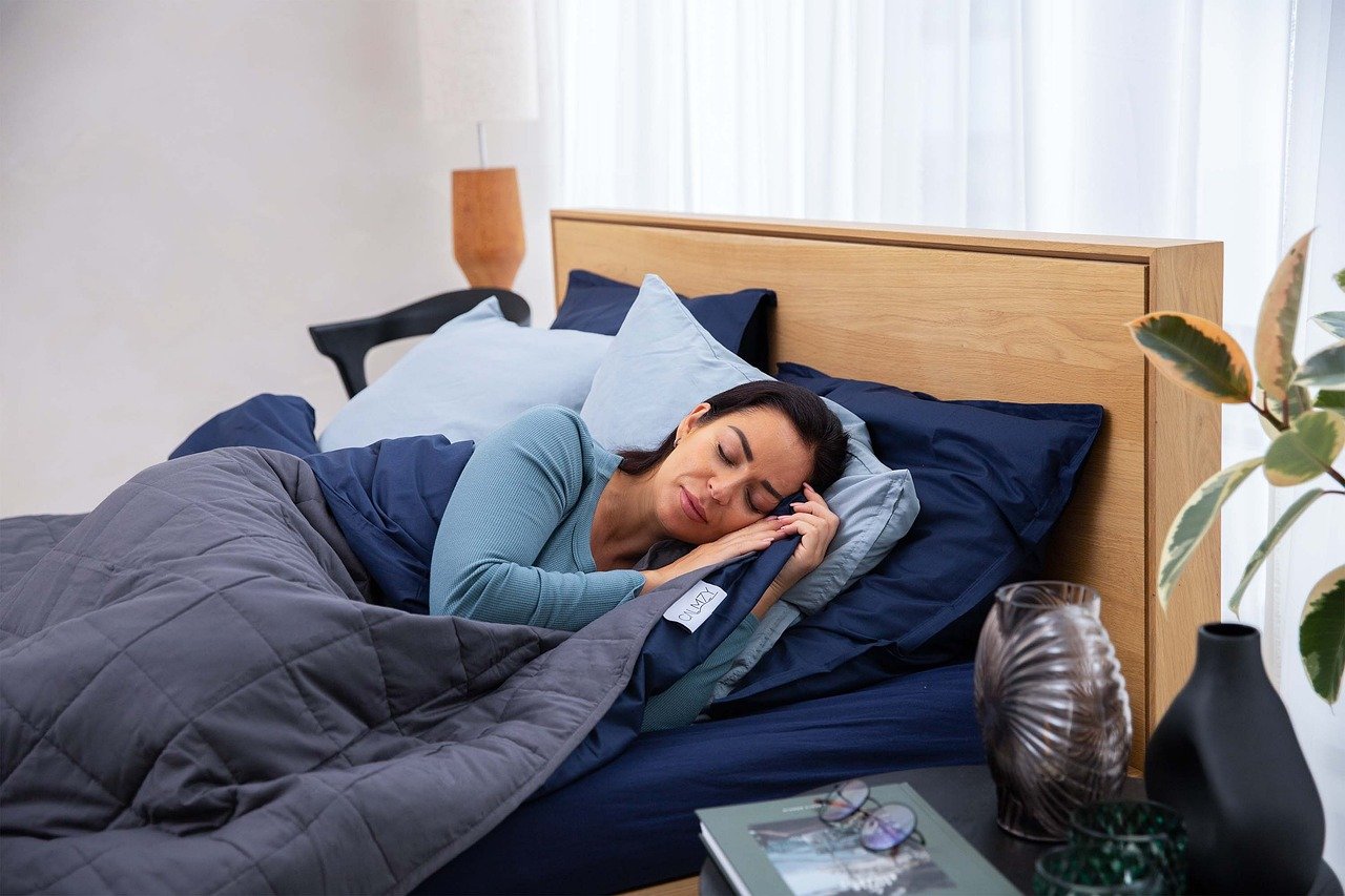 Mujer durmiendo en cama con edredón gris y sábanas azules