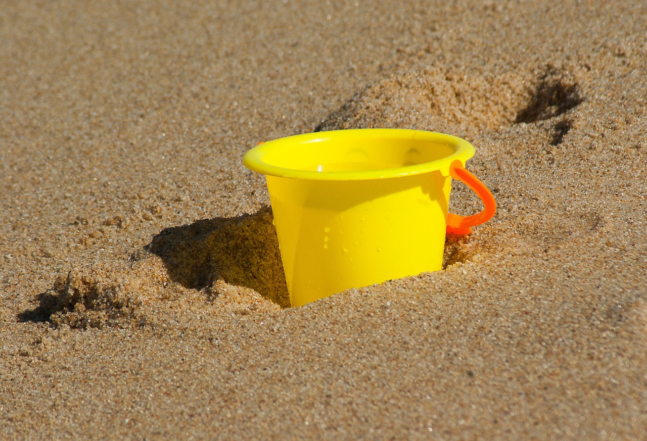 Balde de playa amarillo sobre la arena