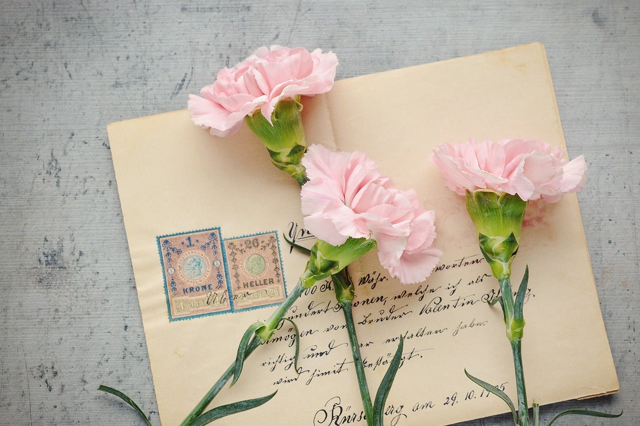 Tres flores rosas encima de un sobre postal