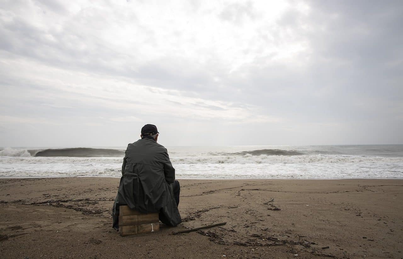 Hombre desganado sentado frente al mar