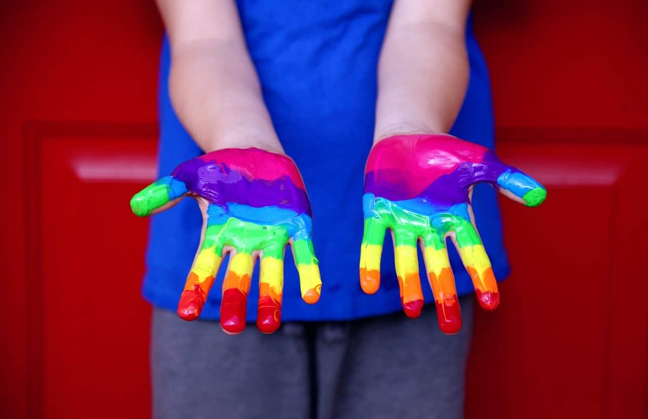 Persona con las manos pintadas con los colores del arcoiris