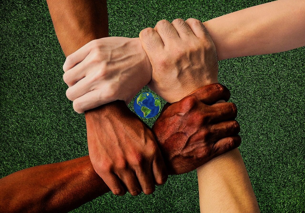 Cuatro personas de diferentes razas tomándose los brazos