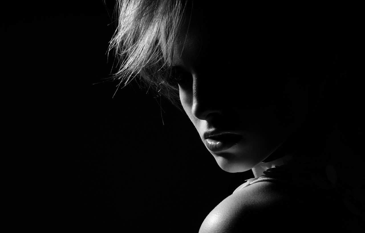 Mujer retratada en blanco y negro, casi en la oscuridad.