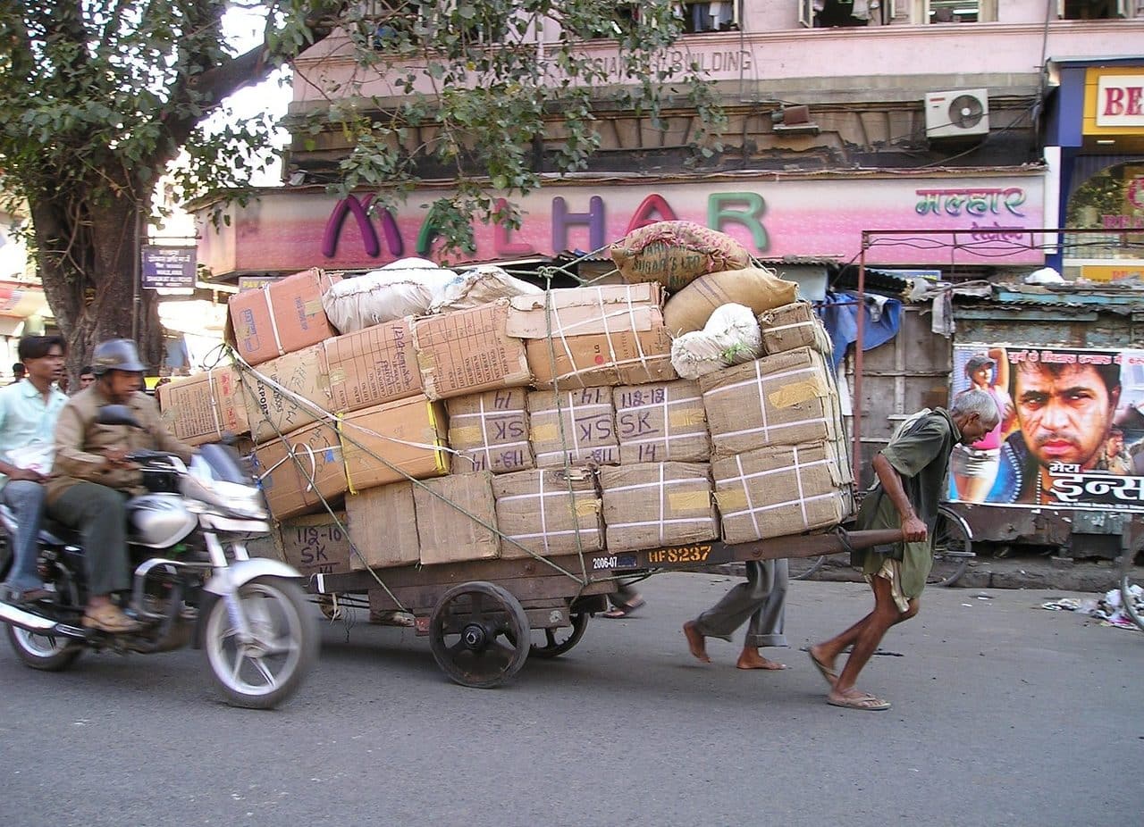 Hombre tirando de un carro cargado de cajas de cartón