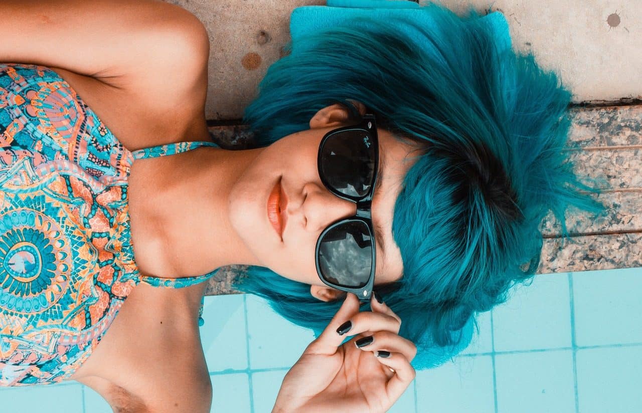 Mujer joven con cabello azul y gafas de sol