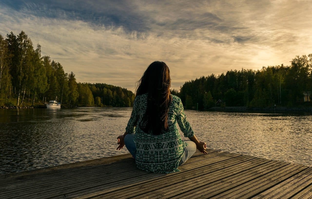 Mujer meditando junto a un lago