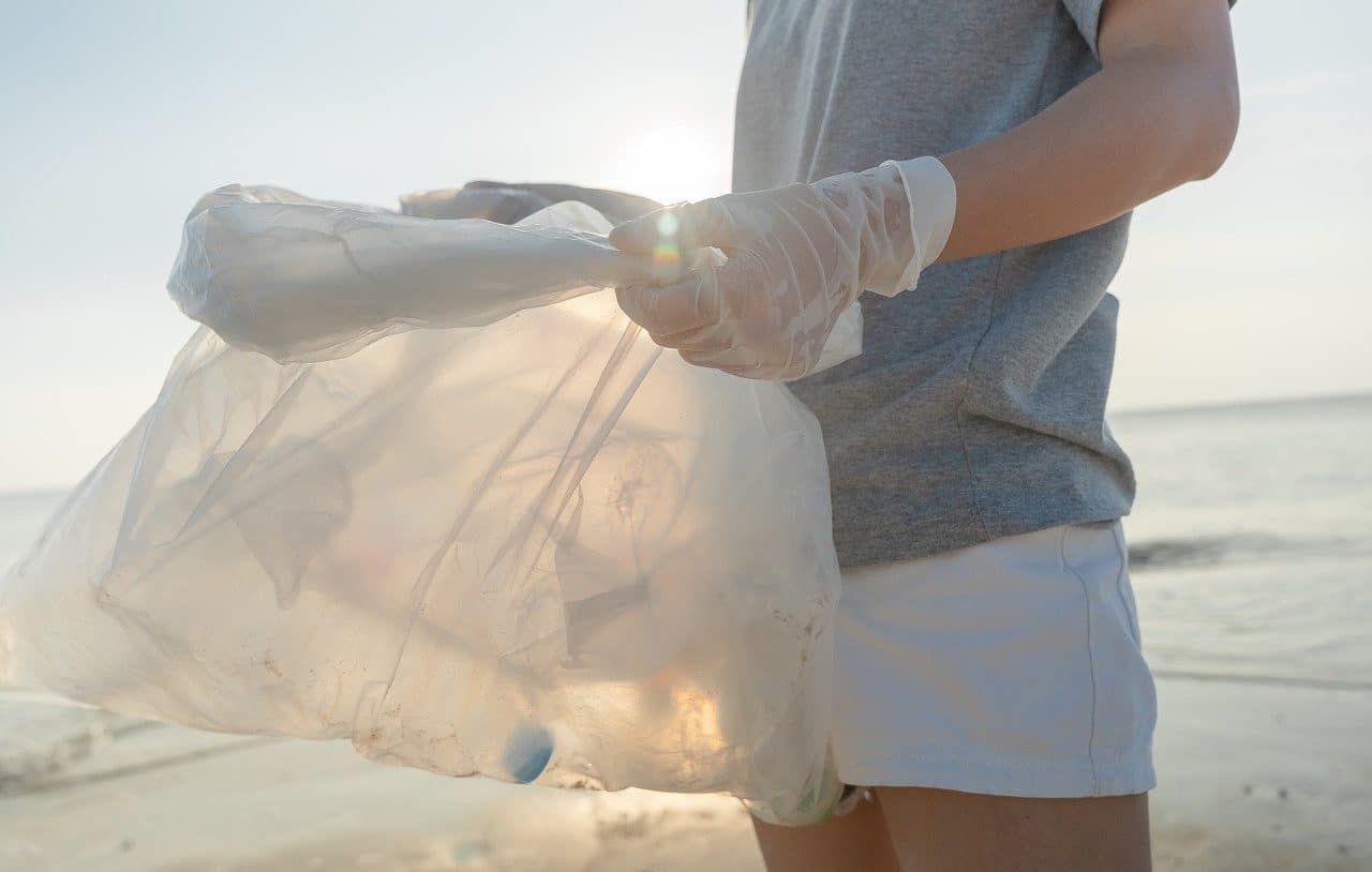 Mujer recogiendo plástico en la playa