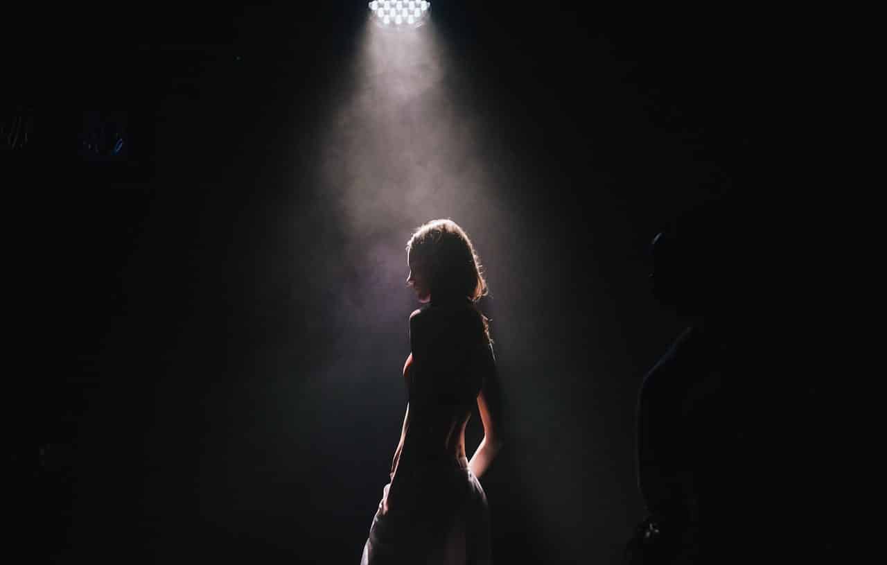 Mujer iluminada por un foco en la oscuridad