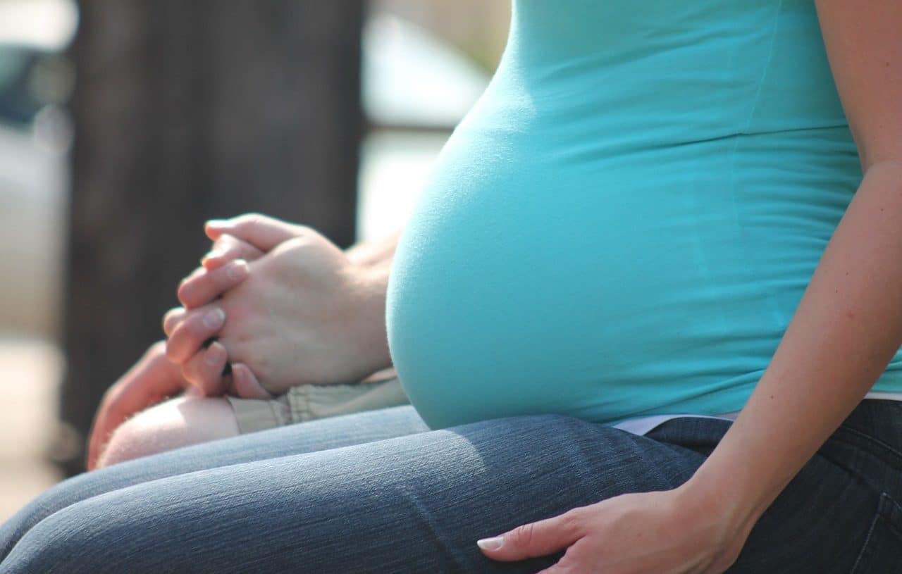 Mujer embarazada sentada en un banco de plaza