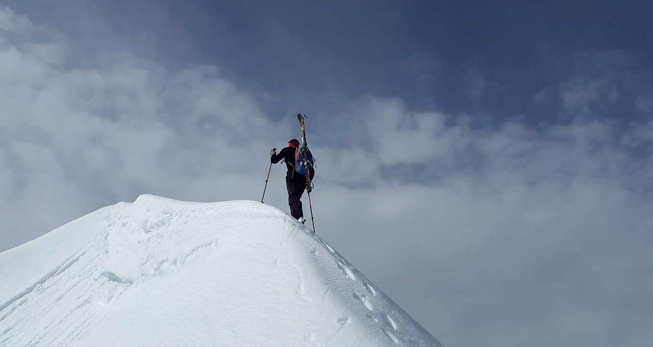 Alpinista en la cima de una montaña nevada