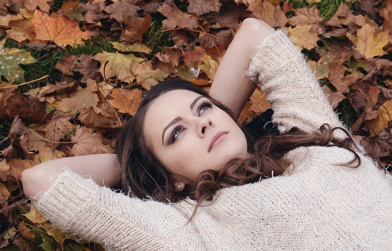 Mujer joven recostada sobre hojas secas