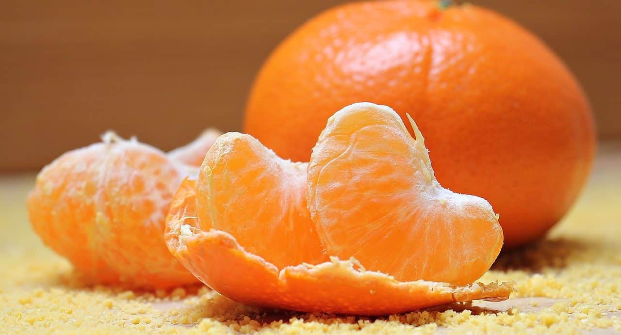Gajos de naranja frente a una naranja entera