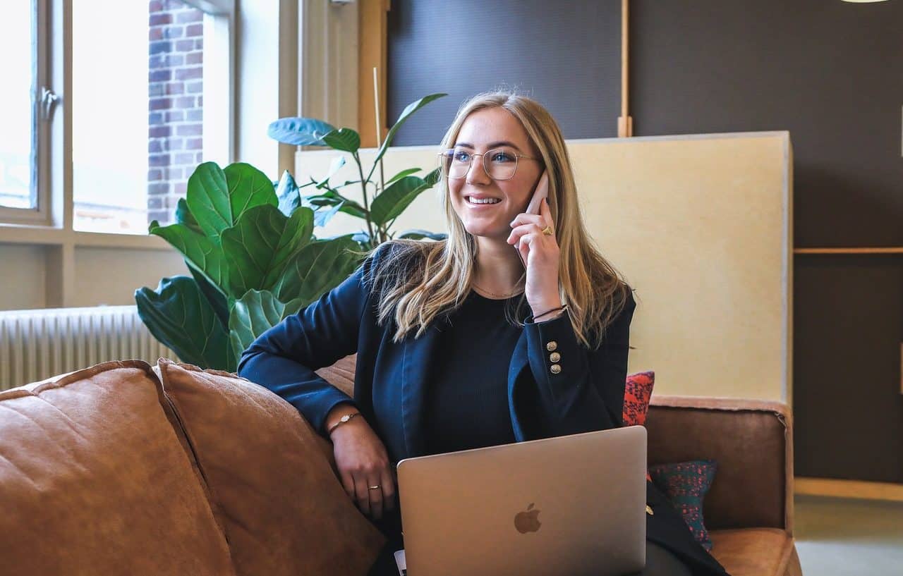 Mujer empresaria hablando por teléfono y usando un ordenador portátil de Apple