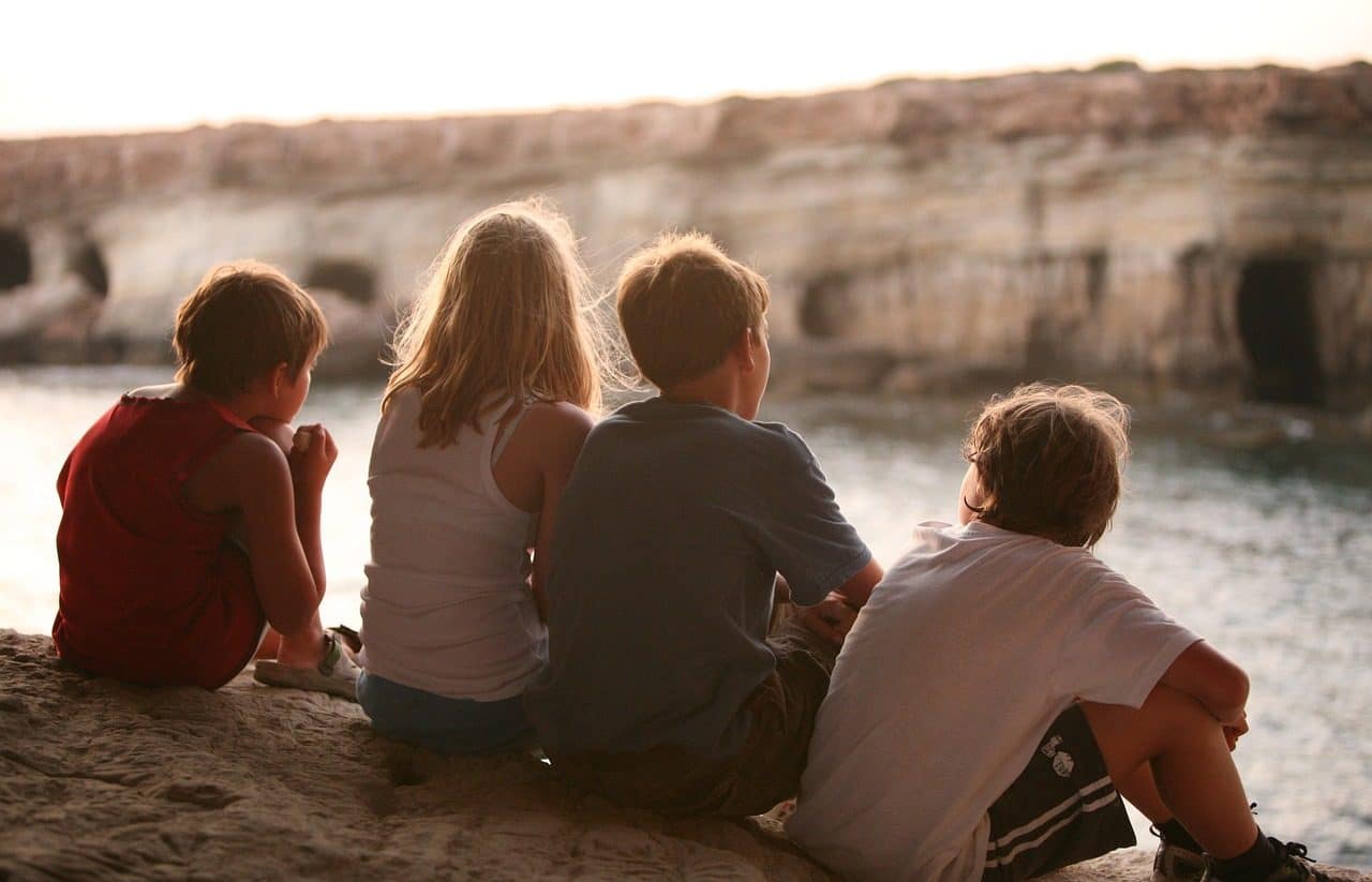 Cuatro niños sentados frente a un lago