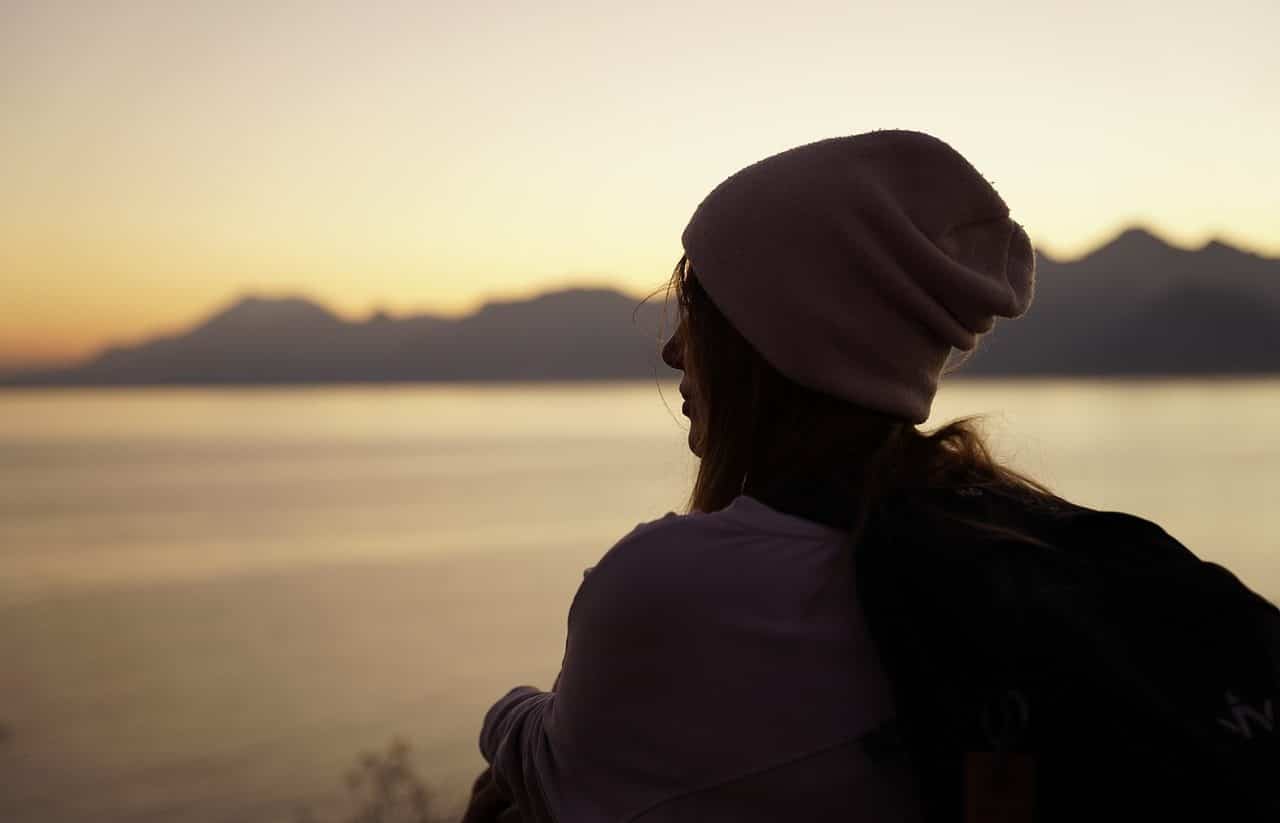 Mujer joven mirando el mar al atardecer