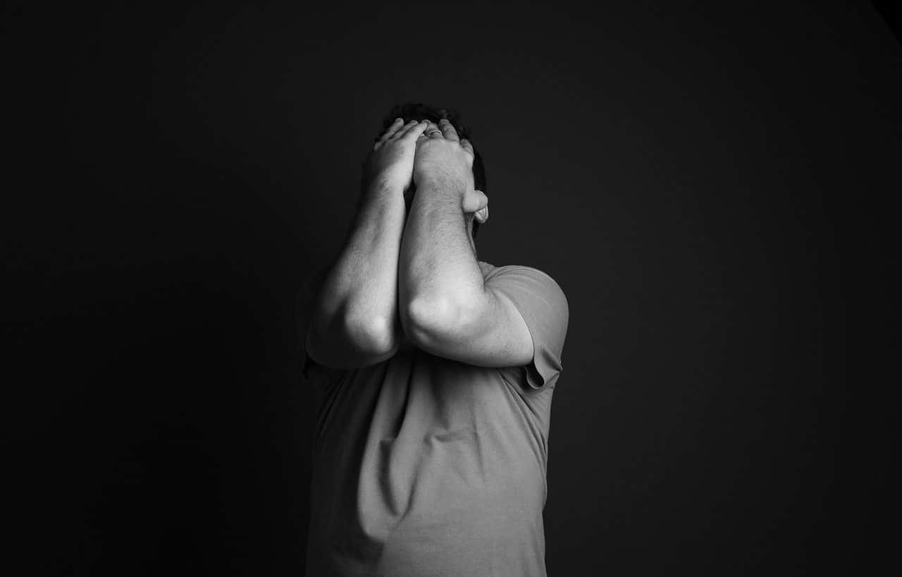 Hombre cubriéndose el rostro con las manos. Fotografía a blanco y negro