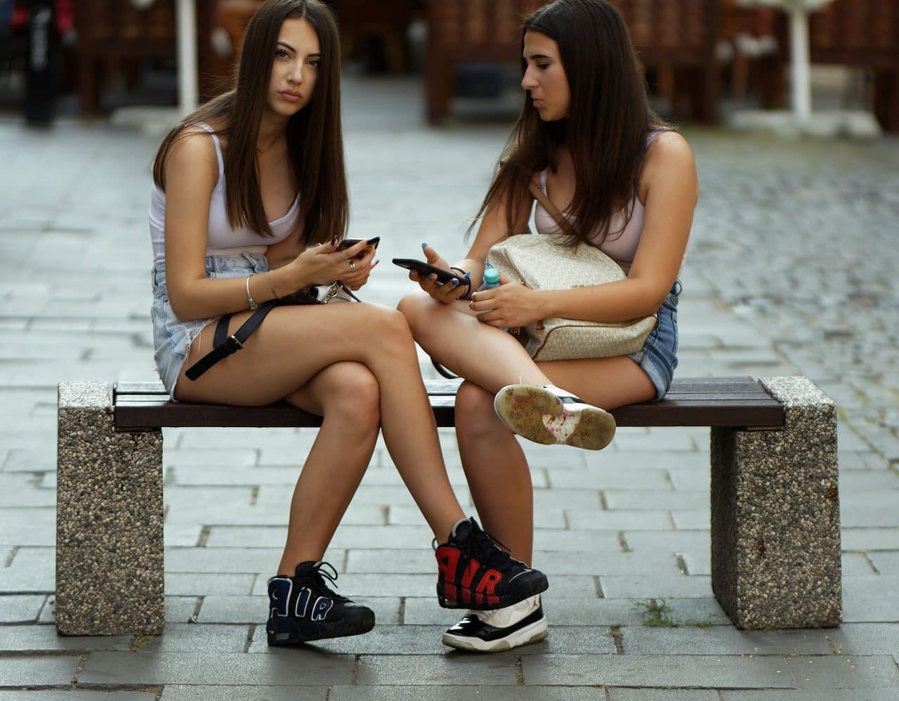 Dos adolescentes sentadas en un banco de plaza