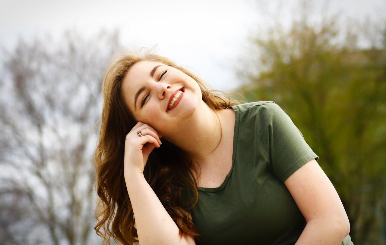 Mujer joven sonriendo y apoyando su cabeza sobre una mano