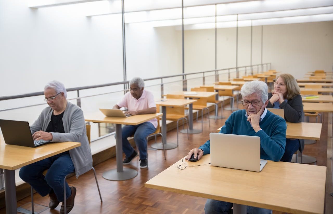 Personas mayores usando ordenadores en aula de escuela