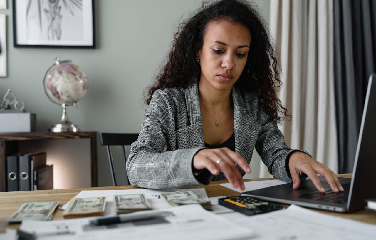 Mujer trabajando en su escritorio con su ordenador portátil y su calculadora