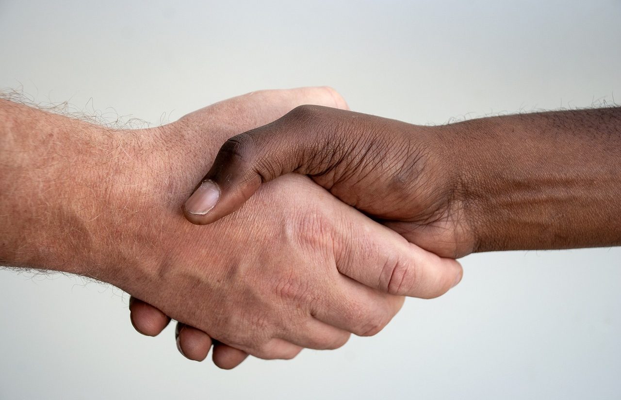 Un hombre negro y uno blanco estrechando sus manos