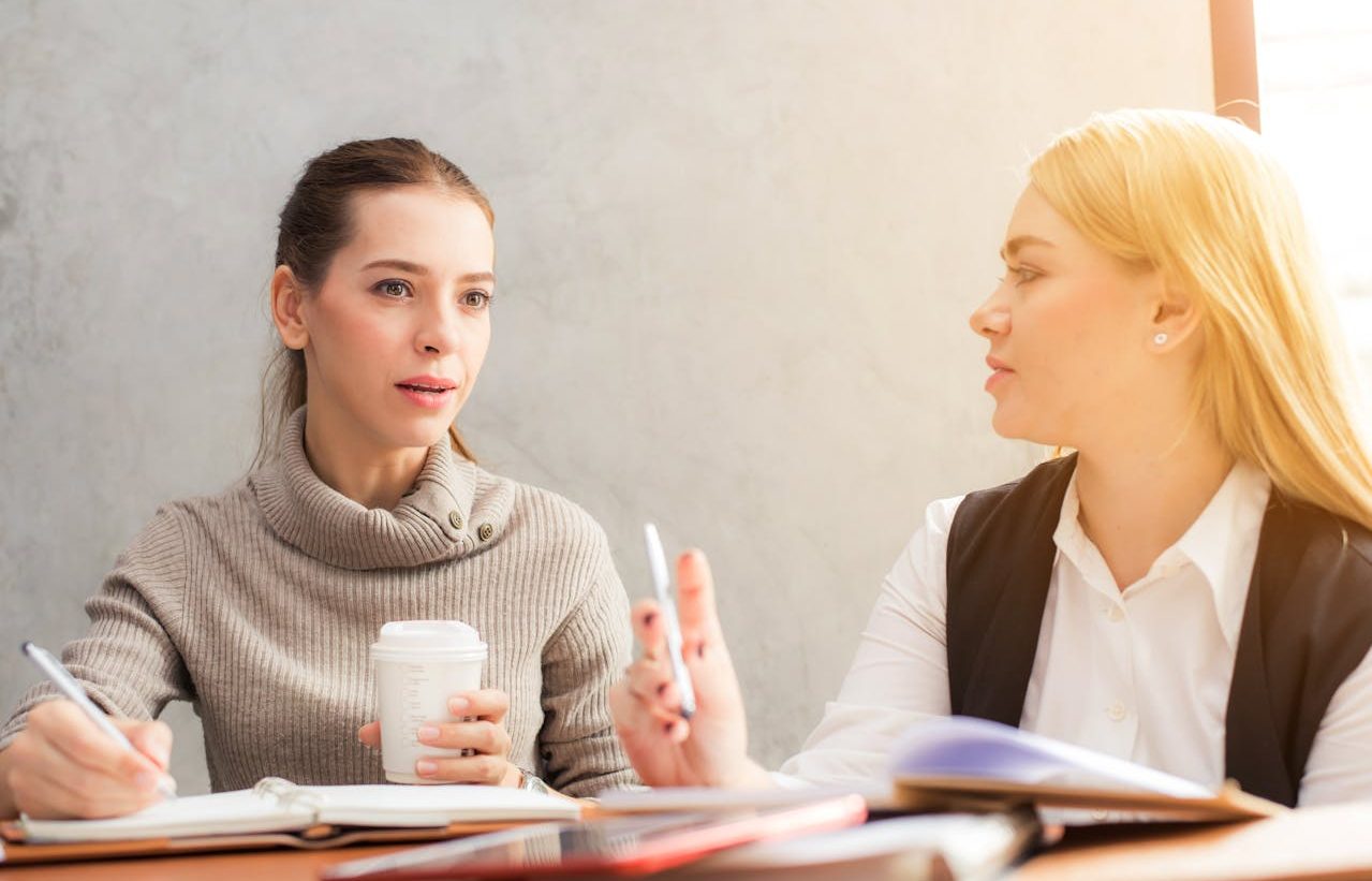 Dos compañeras de trabajo conversando