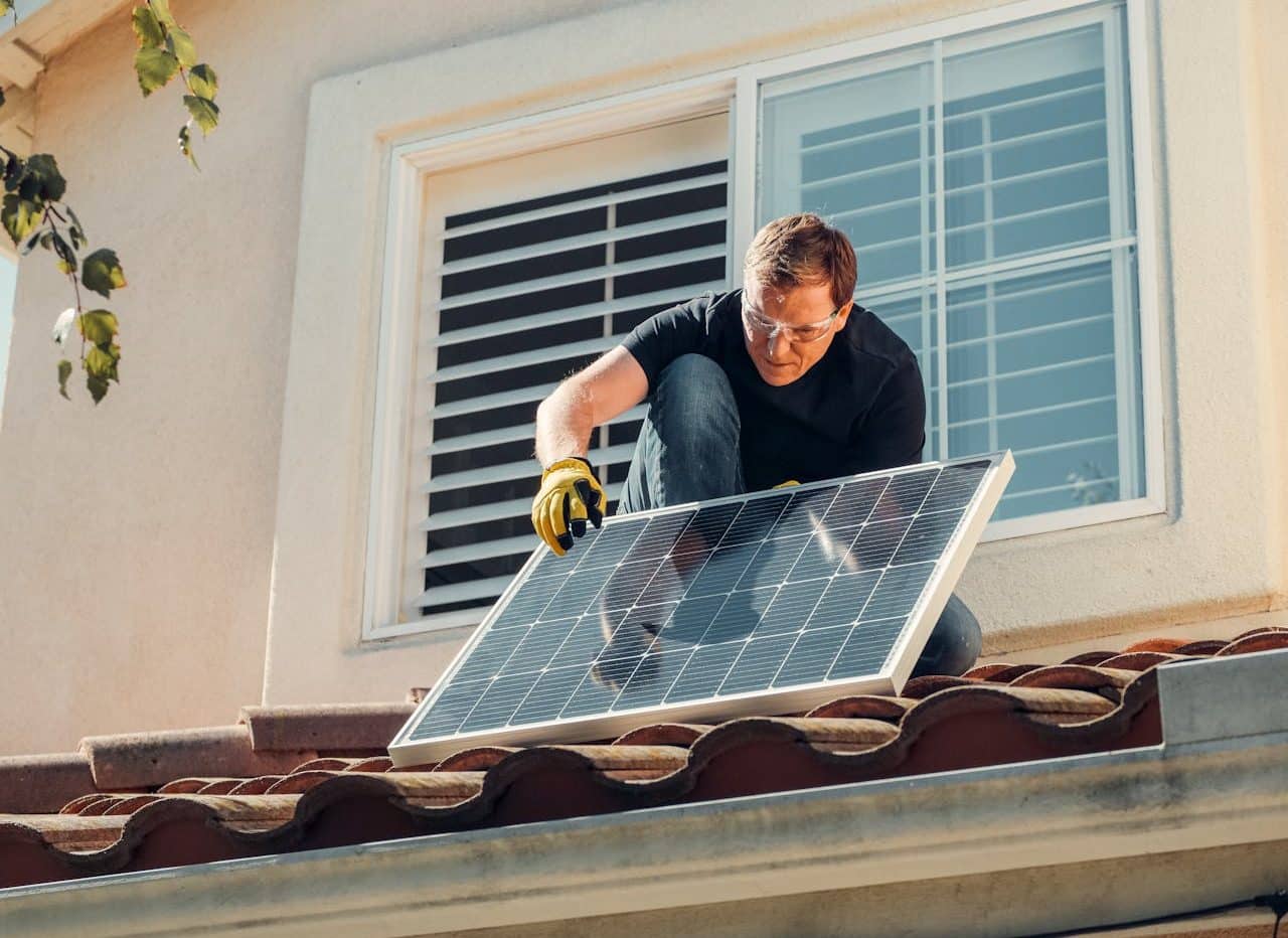 Hombre instalando panel solar en el techo de su casa