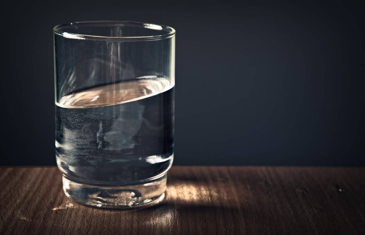 Vaso de agua sobre una mesa con fondo oscuro