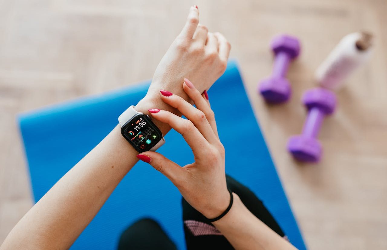 Mujer sobre alfombrilla de ejercicio revisando su reloj para el seguimiento de fitness