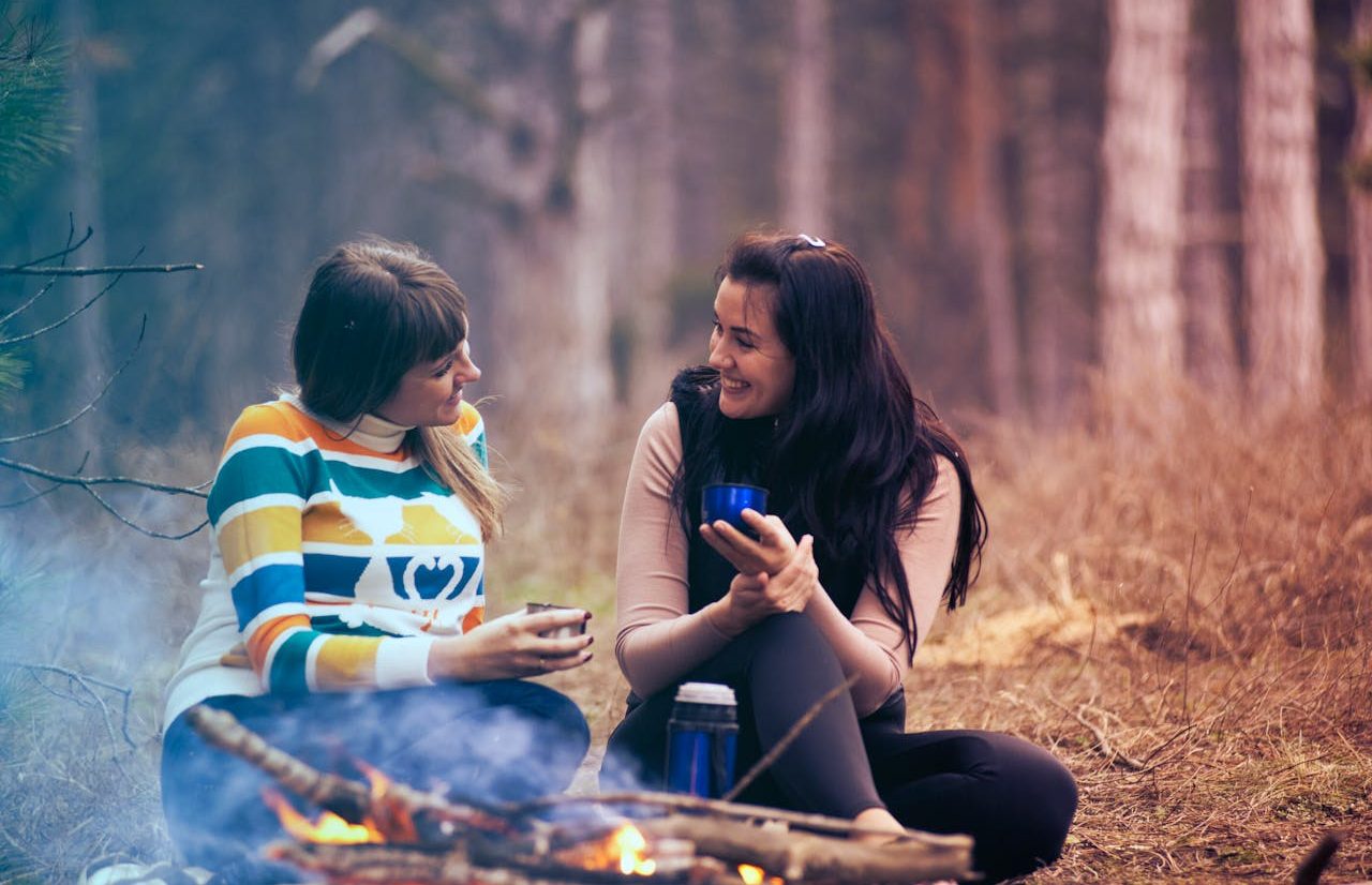 Dos mujeres conversando sentadas en el bosque