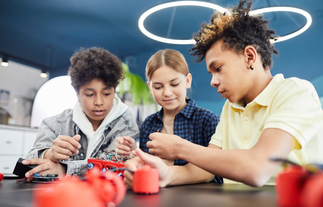 Una niña y dos niños haciendo experimentos electrónicos