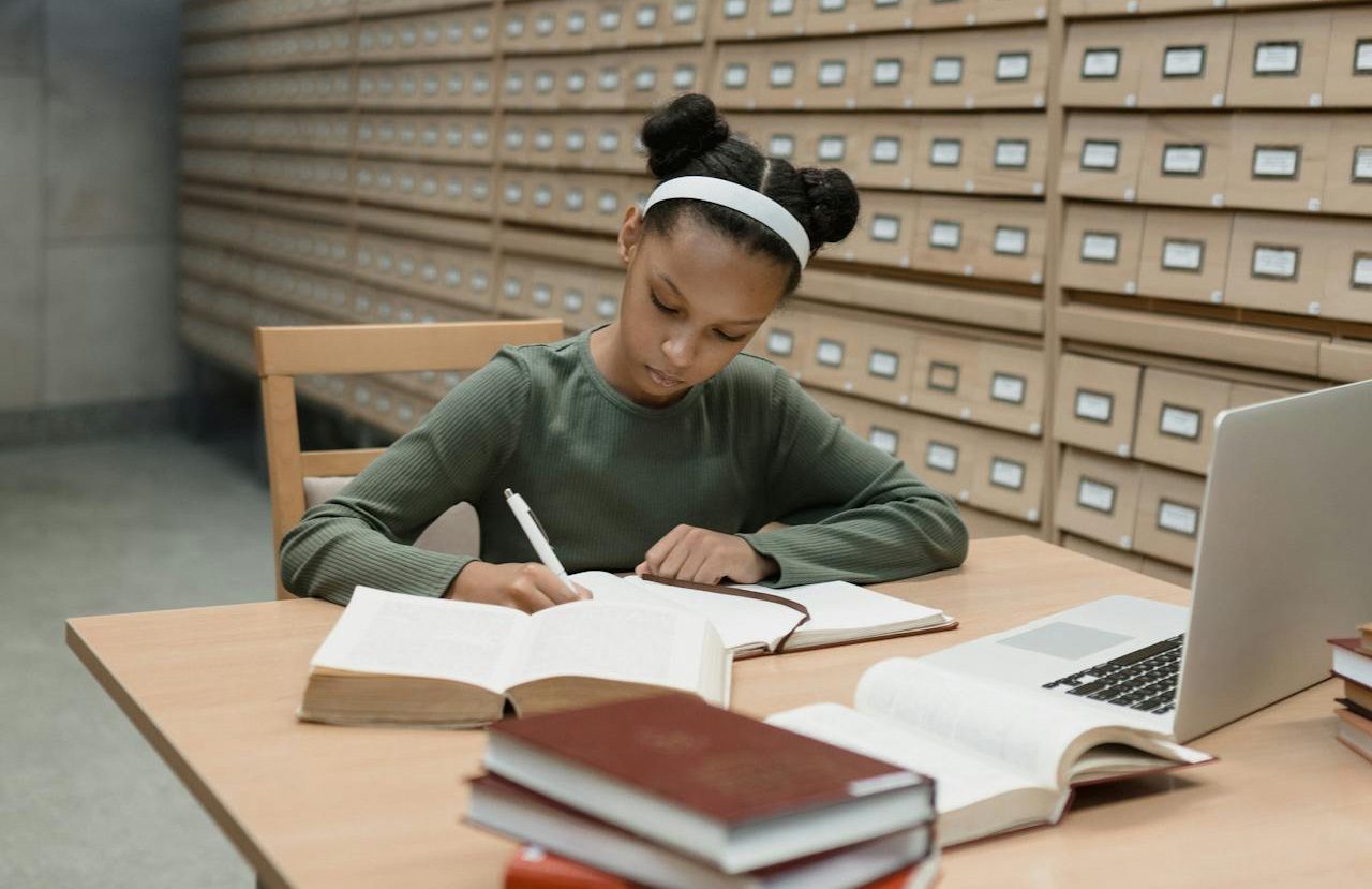 Muchacha tomando notas de sus consultas bibliográficas en una biblioteca