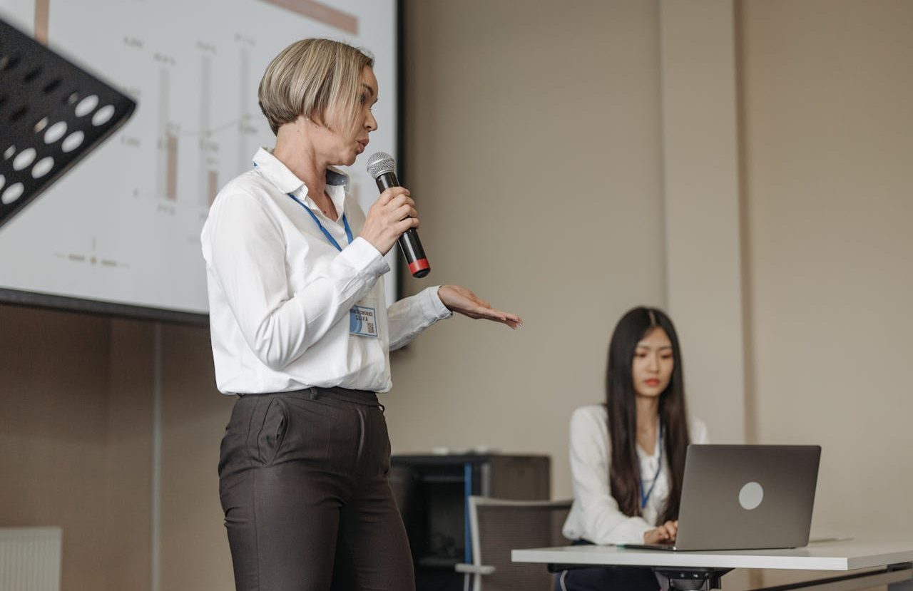 Mujer dando una presentación frente a una pantalla de proyección.