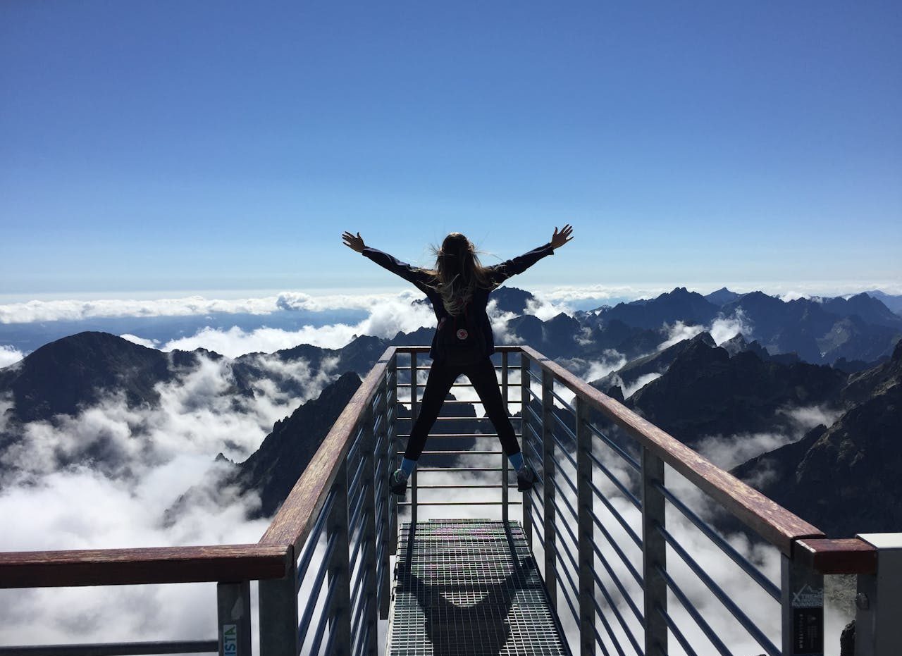 Mujer con los brazos abiertos en la cima de una montaña