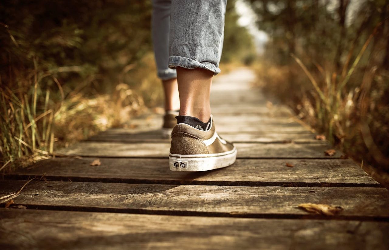 Toma de los pies de una persona avanzando por un camino de madera en la naturaleza