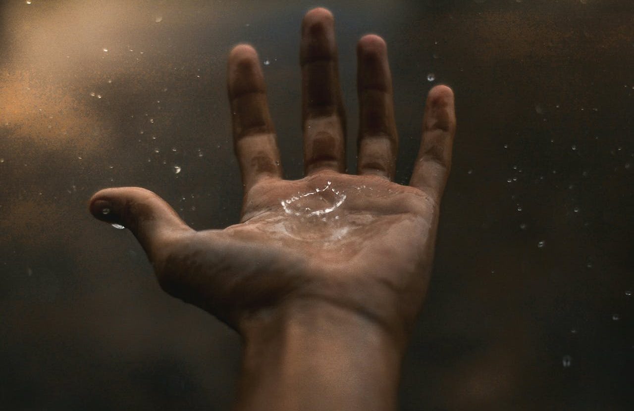 Gota de agua cayendo sobre una mano