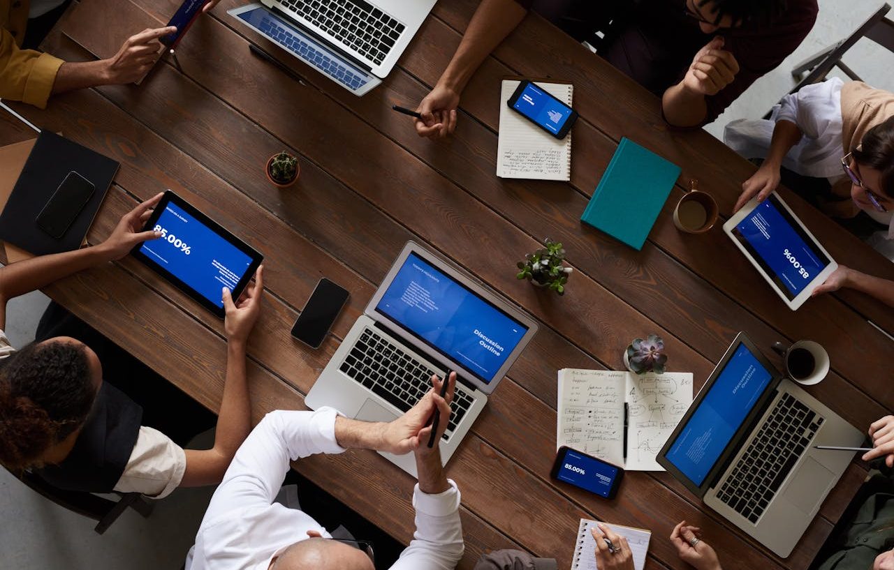 Empleados ejecutivos reunidos. Sentados alrededor de una mesa con ordenadores, teléfonoes, tabletas y docuemntos