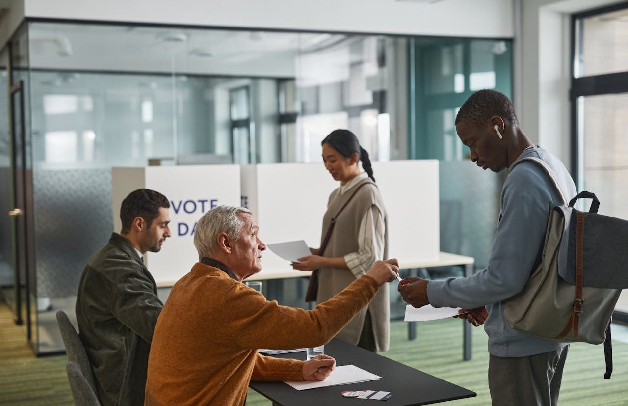 Dos personas entregando sus votos en una mesa electoral