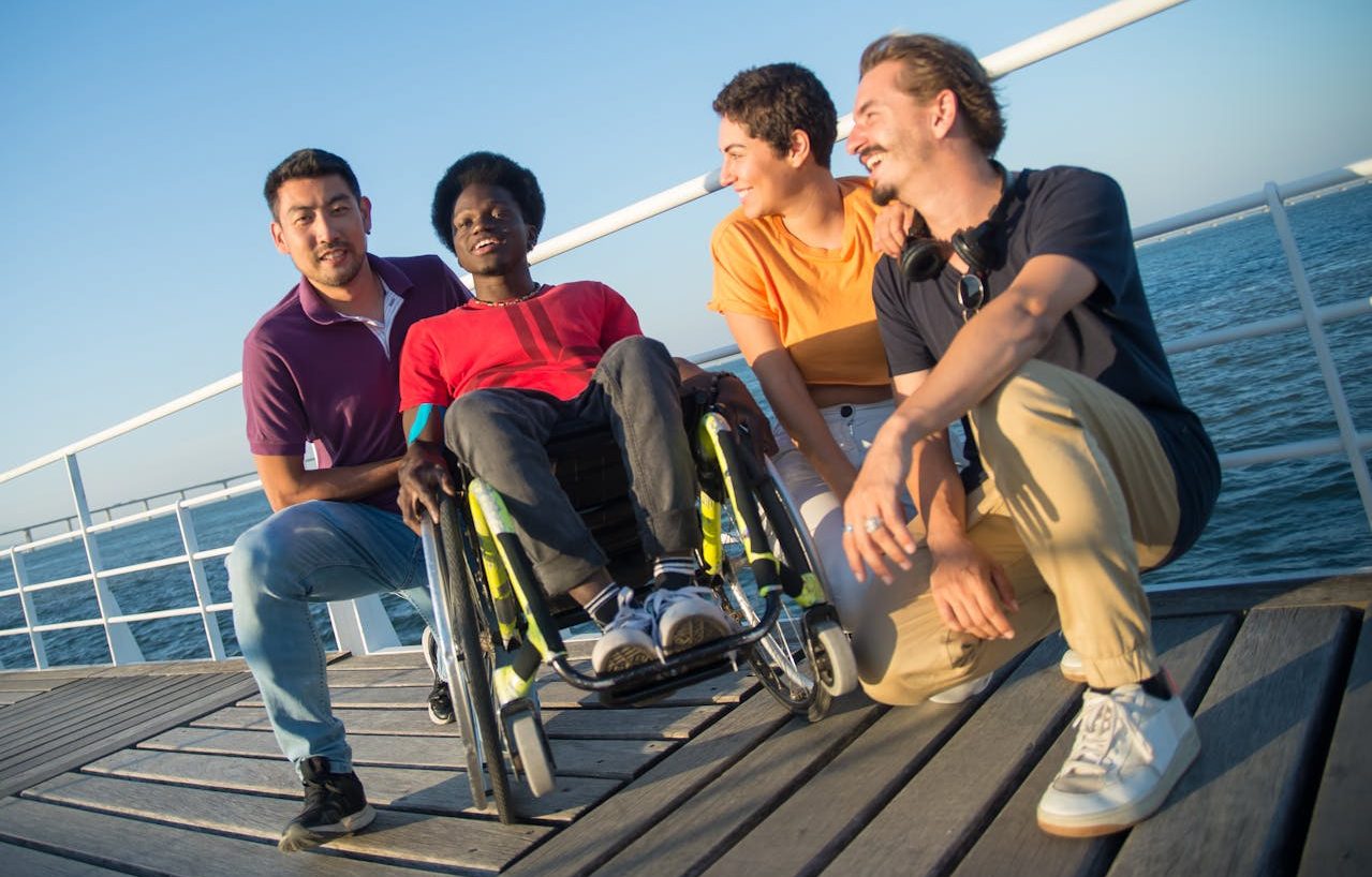 Grupo de amigos junto al mar. Una de las personas está en silla de ruedas