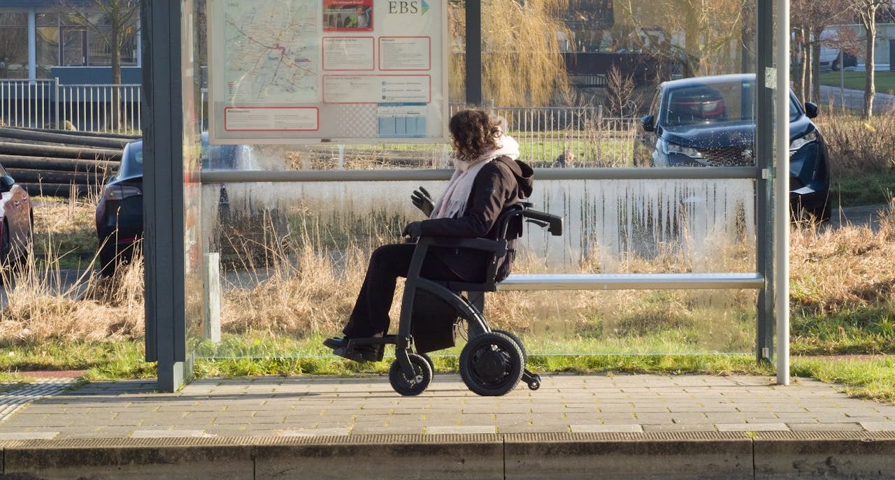 Mujer en silla de ruedas esperando el autobús