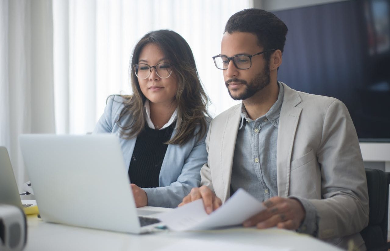Dos personas frente a un ordenador portátil blanco