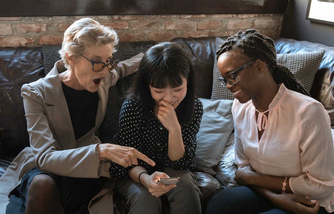 Tres mujeres en un sofá mirando un teléfono