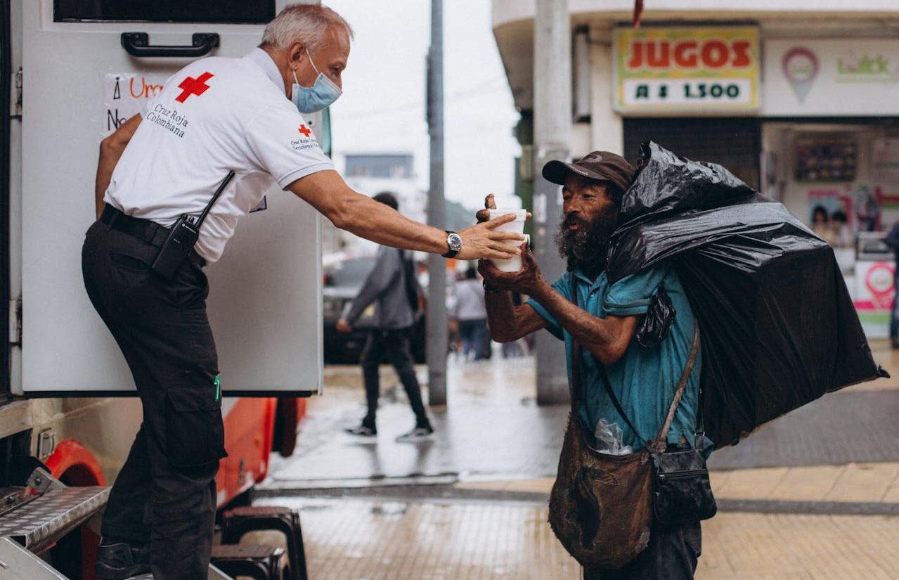 Persona de la Cruz Roja ayudando a hombre sin techo