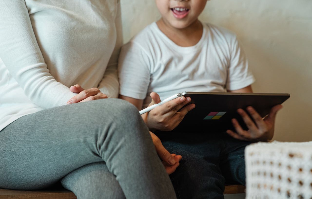 Niño usando una tableta junto a su madre