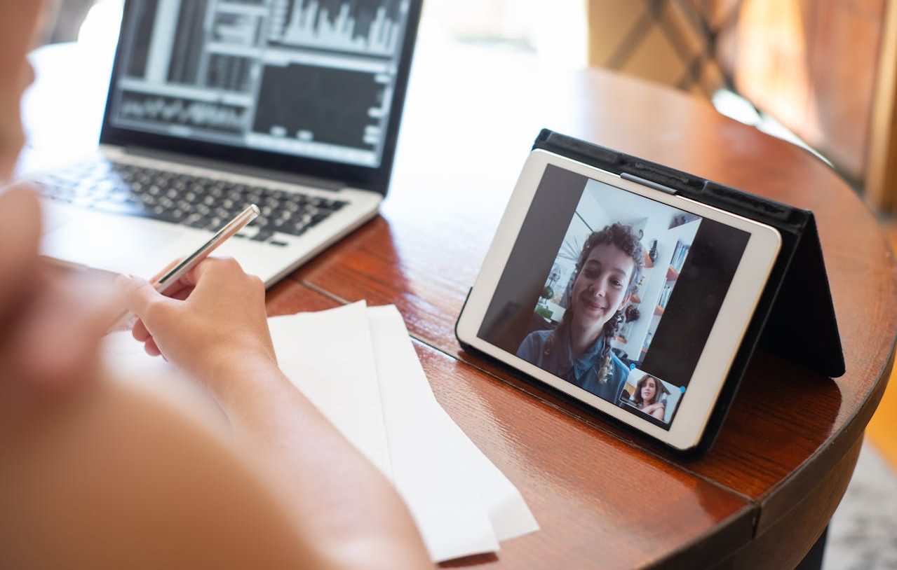 Usando un ordenador portátil y participando de una videoconferencia por medio de una tableta