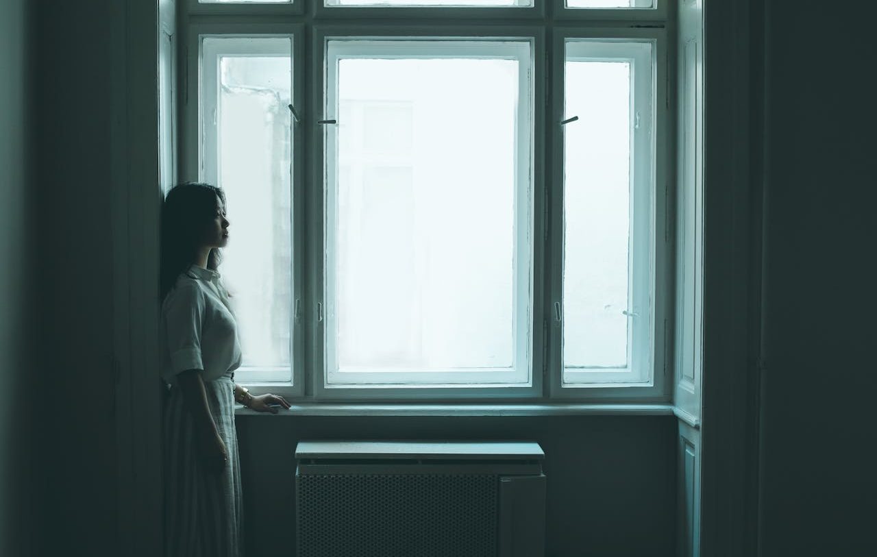 Una mujer joven junto a una ventana a oscuras